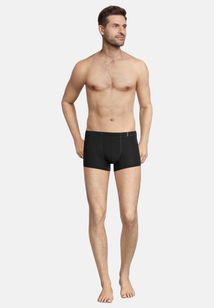 Boxer shorts neri realizzati in tessuto con accenti di cucitura verde, caratterizzati da una forma aderente, una vita elastica e senza loghi visibili.