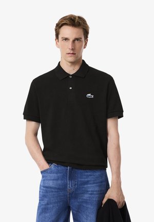 Zwarte katoenen polo met een klassieke kraag, korte mouwen, twee knopen en een klein blauw krokodillenlogo op de linkerborst.