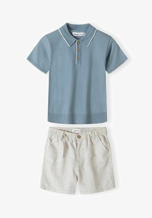 Niebieska koszulka polo z krótkim rękawem i drewnianymi guzikami, zestawiona z beżowymi szortami z elastyczną talią, wyposażonymi w przednie kieszenie i zapięciem na guzik.