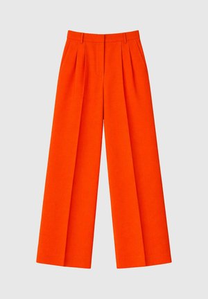 Pantalon large taille haute orange vif avec plis, passants de ceinture et un devant net sur un fond neutre.