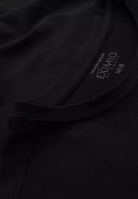 Sort T-shirt med rund hals. Glat bomuldsstof, forstærkede sømme og et mærke med teksten "EXIMIO, Premium Kvalitet, M."