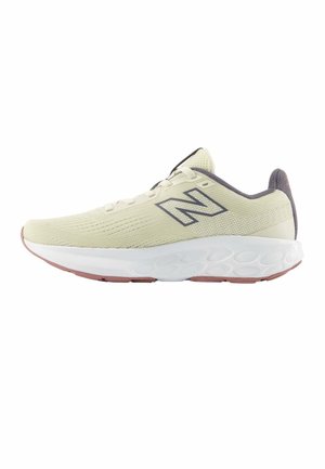 Zapatilla deportiva beige claro con logo "N" gris, parte superior de malla, entresuela blanca acolchada y suela exterior tintada en rosa, mostrada desde un lateral.