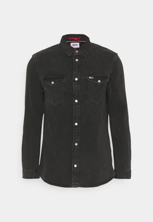 Camisa vaquera negra de manga larga con cierre de botones en la parte delantera, dos bolsillos con solapa en el pecho y discreto logo de Tommy Jeans en el bolsillo derecho.