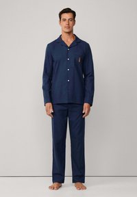 Conjunto de pijama de algodón azul marino que incluye una camisa con botones, un bolsillo y detalles bordados, combinado con pantalones a juego, sin estampados y con un corte relajado.