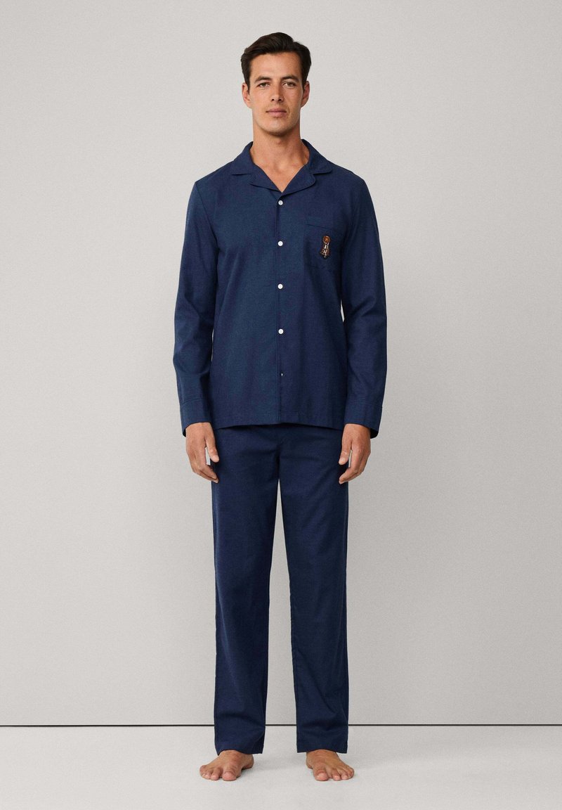 Conjunto de pijama de algodón azul marino que incluye una camisa con botones, un bolsillo y detalles bordados, combinado con pantalones a juego, sin estampados y con un corte relajado.