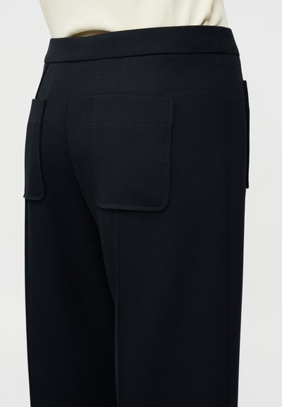 Μαύρο παντελόνι με ραφές, με λεία υφή, διαθέτει δύο μεγάλες τσέπες πίσω και εφαρμοστό ζωνάκι στη μέση.