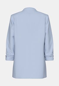 Svetle modrý blazer s hladkým, strukturovaným designem, se sklopenými rukávy a jednoduchým, čistým švem na zadní straně. Měkká textura tkaniny.