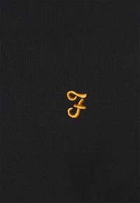 Black knit fabric featuring an embroidered orange "F" logo. The texture is smooth with a close-fitting design.