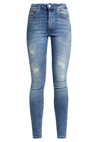 Jeans ajustados de mezclilla en azul claro, con parches desgastados, cintura alta y pierna ceñida. Diseño clásico de cinco bolsillos.