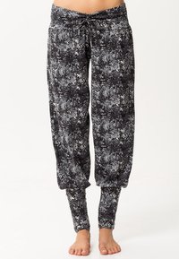 Svart- och vitmönstrade lösa byxor med dragsko i midjan, avsmalnande ben och mjuk textur, lämpliga för avslappnad användning eller yoga.