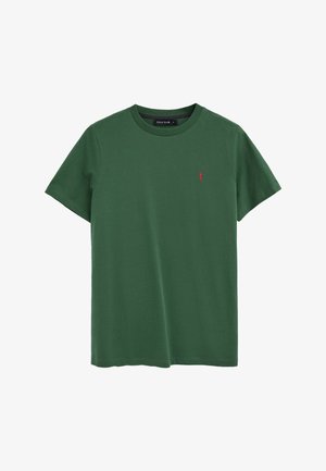 Camiseta verde de manga corta con cuello redondo y pequeño logotipo de figura roja bordada en el lado izquierdo del pecho, etiquetada como Polo Club en el interior del cuello.
