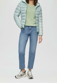 Chaqueta de plumas azul claro, suéter de punto verde, jeans rectos azules, zapatillas plateadas. Textura suave, corte relajado, estilo casual.