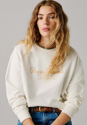 Crèmekleurige sweatshirt met een gouden logo "Pepe Jeans LONDON." Voorzien van een ronde halslijn en geribbelde manchetten, gecombineerd met een blauwe spijkerbroek en een bruine riem.