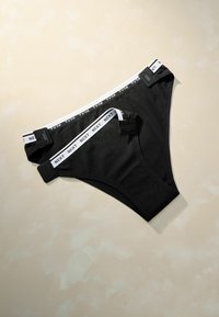 Black cotton briefs with a white elastic waistband featuring "NEXT" logo. The briefs have adjustable clips for fit and a smooth texture.