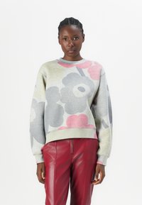 Felpa grigia con motivi floreali colorati, scollatura tonda e maniche lunghe, abbinata a pantaloni in pelle rossa. Tessuto morbido.