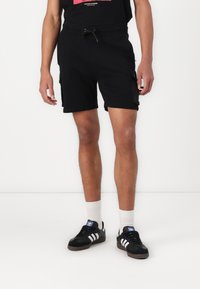 Shorts de sport noirs avec une taille élastique et un cordon de serrage ajustable ; dotés de poches latérales et d'un tissu lisse et léger.