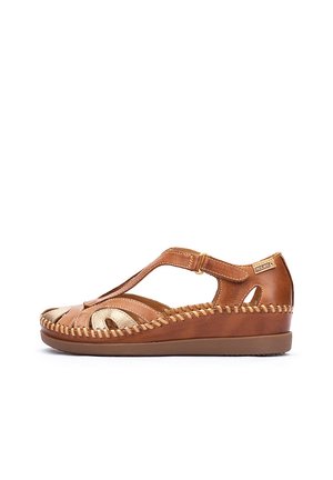 Sandal in pelle marrone con accenti dorati, caratterizzata da un design a T-strap, punta aperta e cuciture dettagliate lungo la suola per un tocco di texture in più.