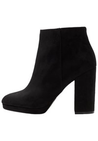 Sort ruskind ankelstøvle med en afrundet tå, høj blokhæl og glat tekstur. Har et sømløst design med minimale detaljer.