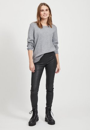 Grå strikkegenser, svarte faux leather leggings og svarte snørboot. Genseren har ribbet kant; leggingsene sitter tett.