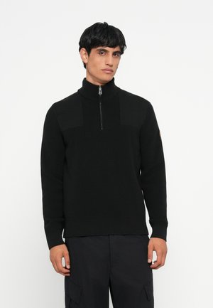 Black knit sweater with a high collar and half-zipper. Features textured panels at the chest and sleeves, and ribbed cuffs and hem.