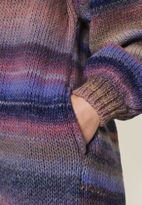 Sweter z dzianiny z kieszenią, w gradientzie fioletowych, niebieskich i różowych odcieni. Prążkowane mankiety oraz materiał z teksturowanej wełny.
