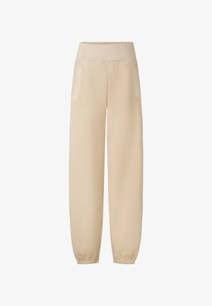Pantalons de jogging beiges avec une large taille élastique, deux poches latérales et des poignets élastiques aux chevilles, fabriqués en tissu doux et léger.