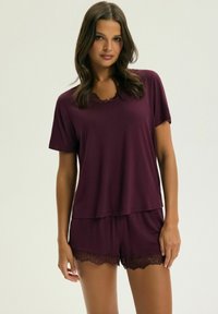 Burgundy sleep set featuring a short-sleeve top with a scalloped neckline and matching shorts with lace trim at the hem. Soft fabric texture.