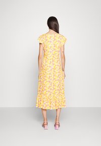 Robe florale jaune avec des manches courtes froncées, taille ajustée et ourlet évasé. Le motif présente des fleurs roses et violettes. Tissu léger.