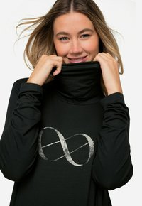 Maglione a maniche lunghe nero con un grafico d'infinito argentato sul davanti. Il tessuto è liscio con un design aderente.