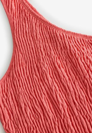 Top de tirantes color coral con un diseño texturizado y fruncido, confeccionado con una tela suave y elástica. Los tirantes se curvan de manera suave para un ajuste cómodo.
