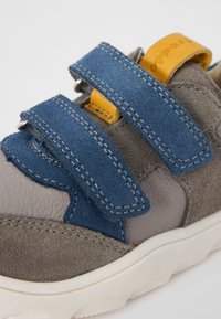 Graue und blaue Wildledersneaker mit gelben Akzenten, ausgestattet mit zwei breiten Klettverschlüssen, strukturiertem Kalbsleder und einer Gummisohle.