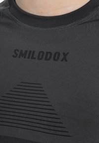 Sort atletisk skjorte med rund halsudskæring. Indeholder et subtilt stripet trekantsmønster og "SMILODOX"-logo i mørkt tryk.