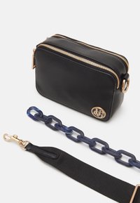 Czarna prostokątna torba wykonana z teksturowanego materiału z złotymi zamkami błyskawicznymi. Zawiera niebieski łańcuszkowy pasek i czarny materiałowy pasek. Ozdobiona detalem logo.