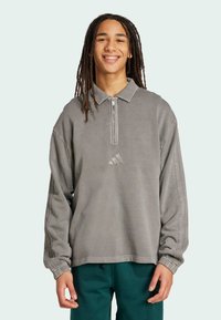 Grå pullover med kvart-zip, krave-design og ribbede manchetter. Har diskret tre-stribe detaljer og præget logo på brystet.