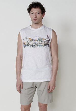 Mouwloos wit katoenen T-shirt met kleurrijke palmboomafbeelding en tekstprint; gecombineerd met lichtgrijze korte broek, gladde textuur.