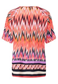 Blouse multicolore avec un motif en zigzag orange, rose et noir, à manches courtes et encolure ronde.