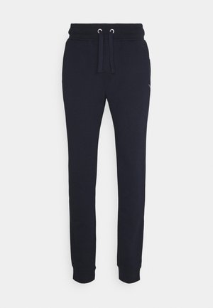 Pantalon de jogging bleu marine avec taille élastique, cordon ajustable, bas resserrés aux chevilles et logo discret sur la partie supérieure de la cuisse.
