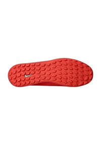 Rdeča športna čevlja z teksturiranim podplatom in izrazitimi zadrževalnimi lastnostmi. V bližini središča je majhen srebrni Nike logo.