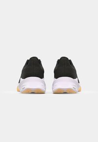 Des chaussures de sport noires avec une tige texturée, une semelle intermédiaire blanche et une semelle extérieure en caoutchouc avec des accents orange. Conception légère pour la performance.