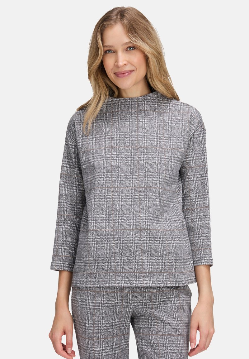 Haut à carreaux gris avec manches trois-quarts, col montant, tissu texturé et coupe décontractée. Remarquable pour ses accents bruns subtils dans le motif.