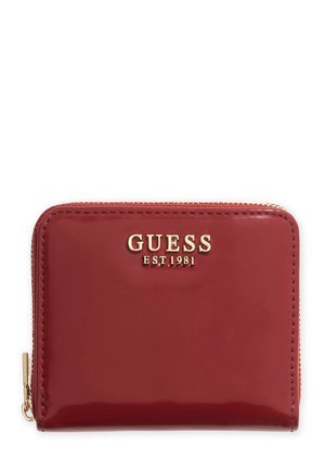 Red patent leather wallet featuring a gold "GUESS EST. 1981" logo and a zipper closure with gold hardware accents. Smooth texture, rectangular shape.