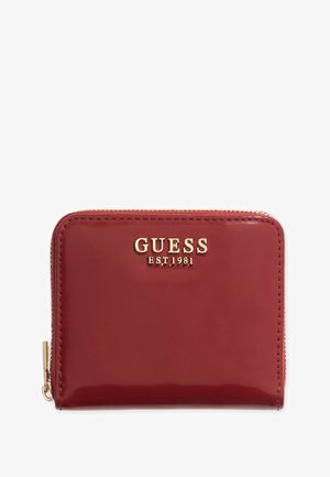 Portefeuille en cuir verni rouge avec un logo doré "GUESS EST. 1981" et une fermeture éclair avec des accents en matériel doré. Texture lisse, forme rectangulaire.