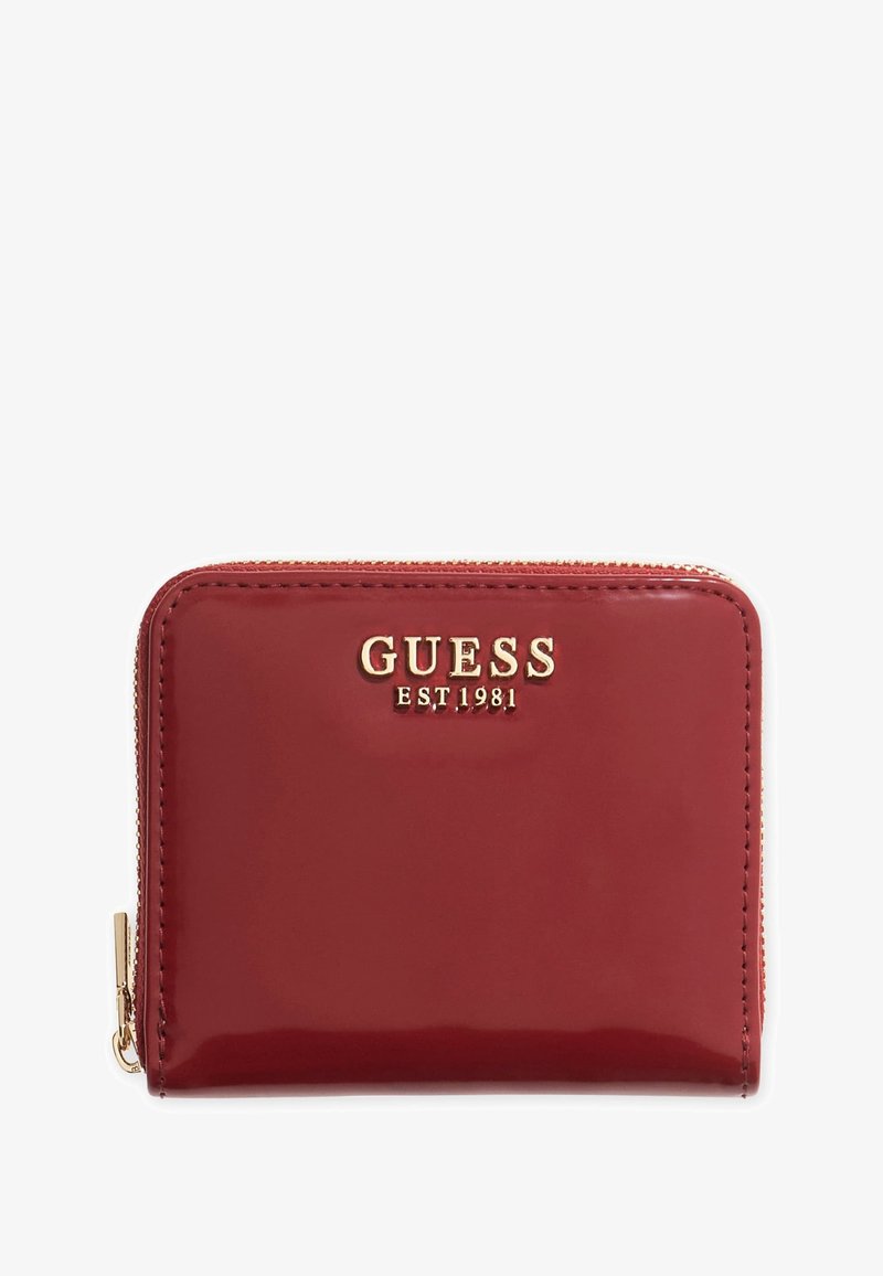 Kirkas punane patenditud nahast rahakott, millel on kuldne "GUESS EST. 1981" logo ja lukuga sulgemine koos kuldsete kinnitusdetailidega. Sujuv tekstuur, ristkülikukujuline kuju.