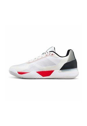 Weißer Sportschuh mit roten und schwarzen Akzenten, Schnürdesign, strukturierter Sohle und gepolstertem Fersenkragen für Halt.