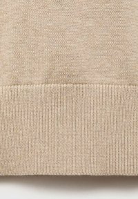 Bežani pleteni pulover z rebrastim robom. Tekstura je mehka, z majhnimi variacijami v barvi, kar nakazuje na udoben dizajn.