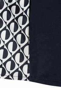 Marineblauer Stoff mit glatter Textur neben einem gemusterten Panel, das schwarz-weiße geometrische Formen zeigt, die Kurven und Quadrate kombinieren.