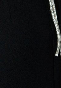Czarna odzież z błyszczącym, srebrnym detalem wzdłuż krawędzi, o gładkiej fakturze i eleganckim, dopasowanym kroju.
