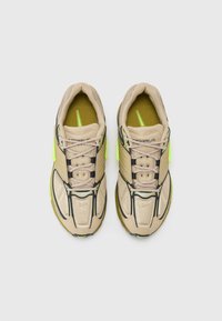 Μπεζ αθλητικά παπούτσια με δικτυωτό άνω μέρος, lime green λεπτομέρειες και μαύρες πινελιές. Διαθέτουν στρογγυλή μύτη και επίπεδη σόλα για σταθερότητα.