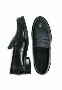 Czarne skórzane mokasyny z lekko podwyższonym obcasem, o gładkiej powierzchni, ozdobnym przeszyciu i pasku na podbiciu.