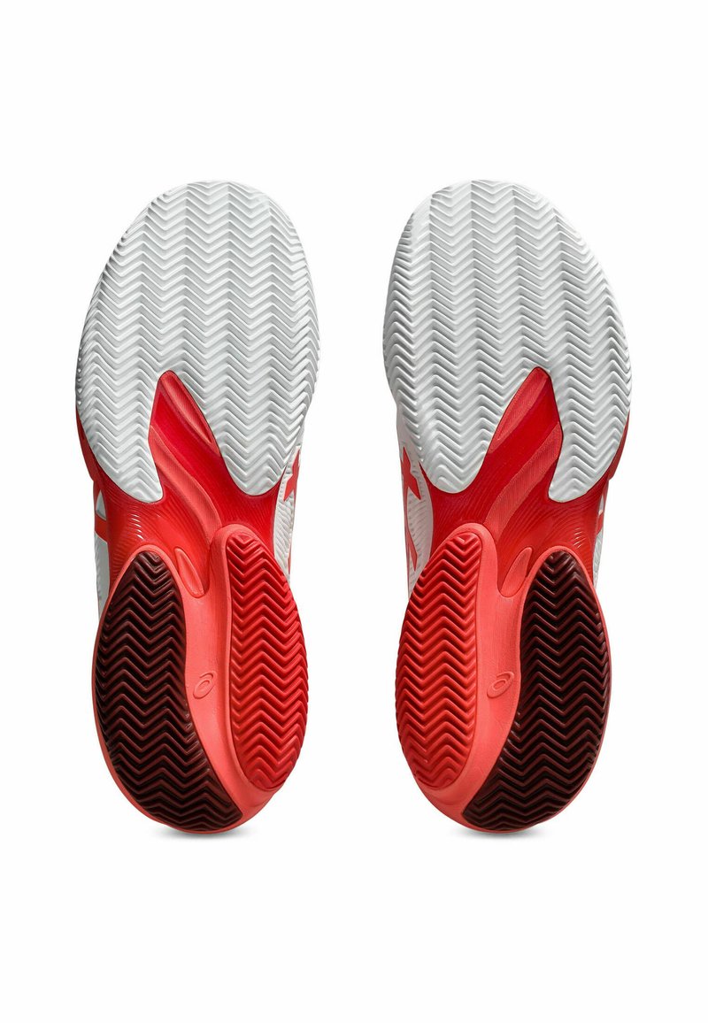 Scarpe da ginnastica rosse e bianche con una suola in gomma strutturata caratterizzata da un motivo a spina di pesce e ritagli per la flessibilità.